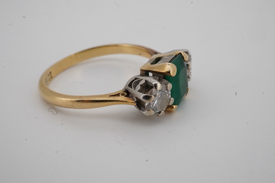 An 18ct, emerald and diamond set three stone ring, size M, gross weight 3.7 grams, (emerald cracked).